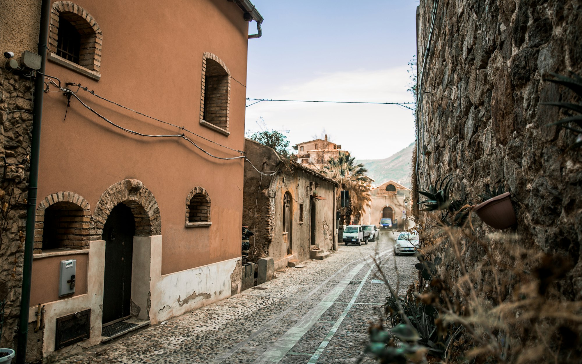 A stone street in an Italian hill town, the road carrying the eye to higher ground in the distance